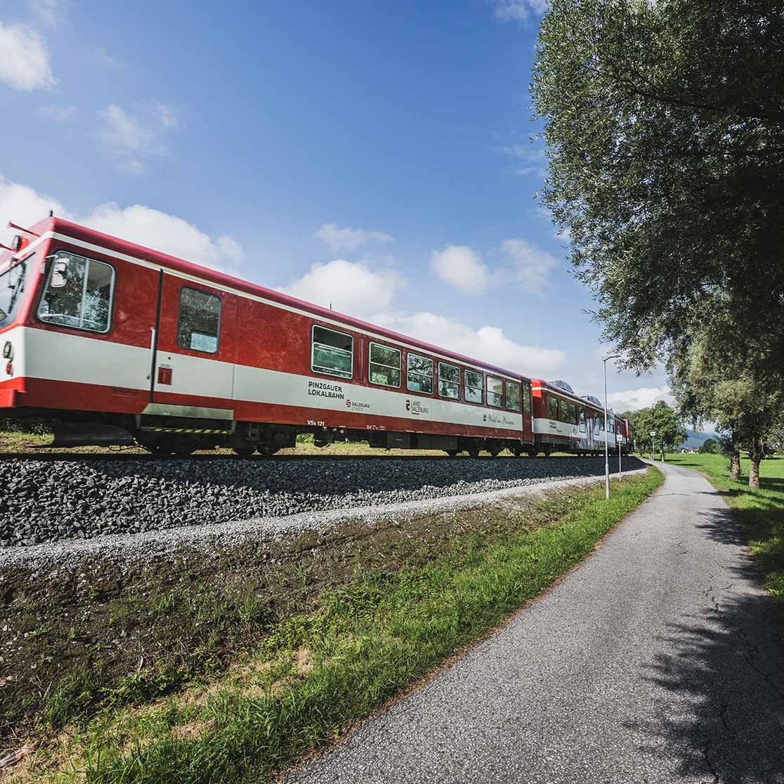 Bild der Pinzgauer Lokalbahn an einem sonnigen Tag in Naturkulisse.