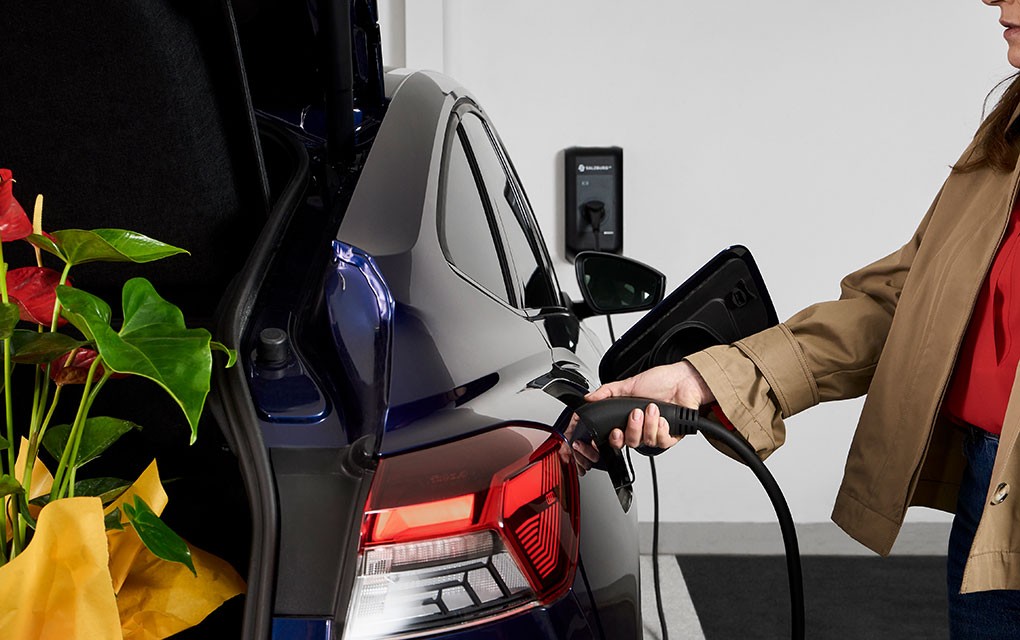 Frau lädt ihr Auto an Wall-Box nach einkauf