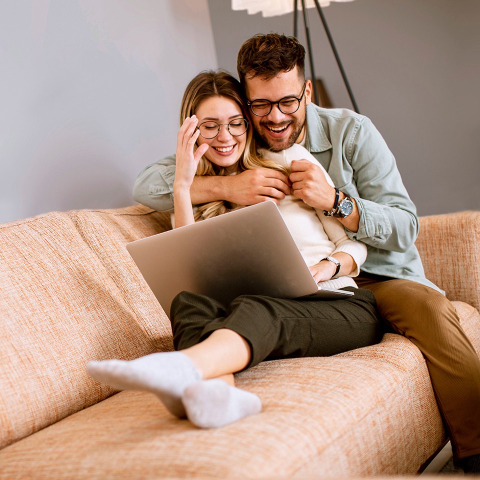 Glückliches Paar auf Sofa mit Laptop.