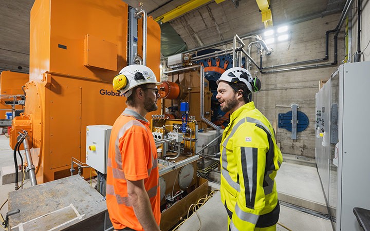 Zwei Mitarbeiter in Warnweste und Schutzkleidung stehen im Inneren des Kraftwerks Stegenwald