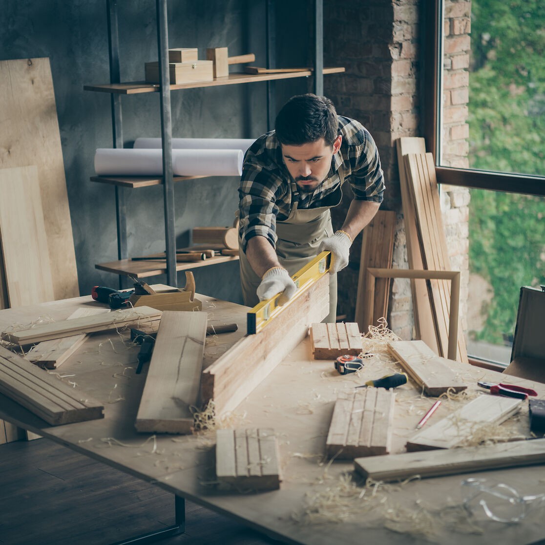 Tischler beim Ausmessen eines Brettes in der Werkstatt.