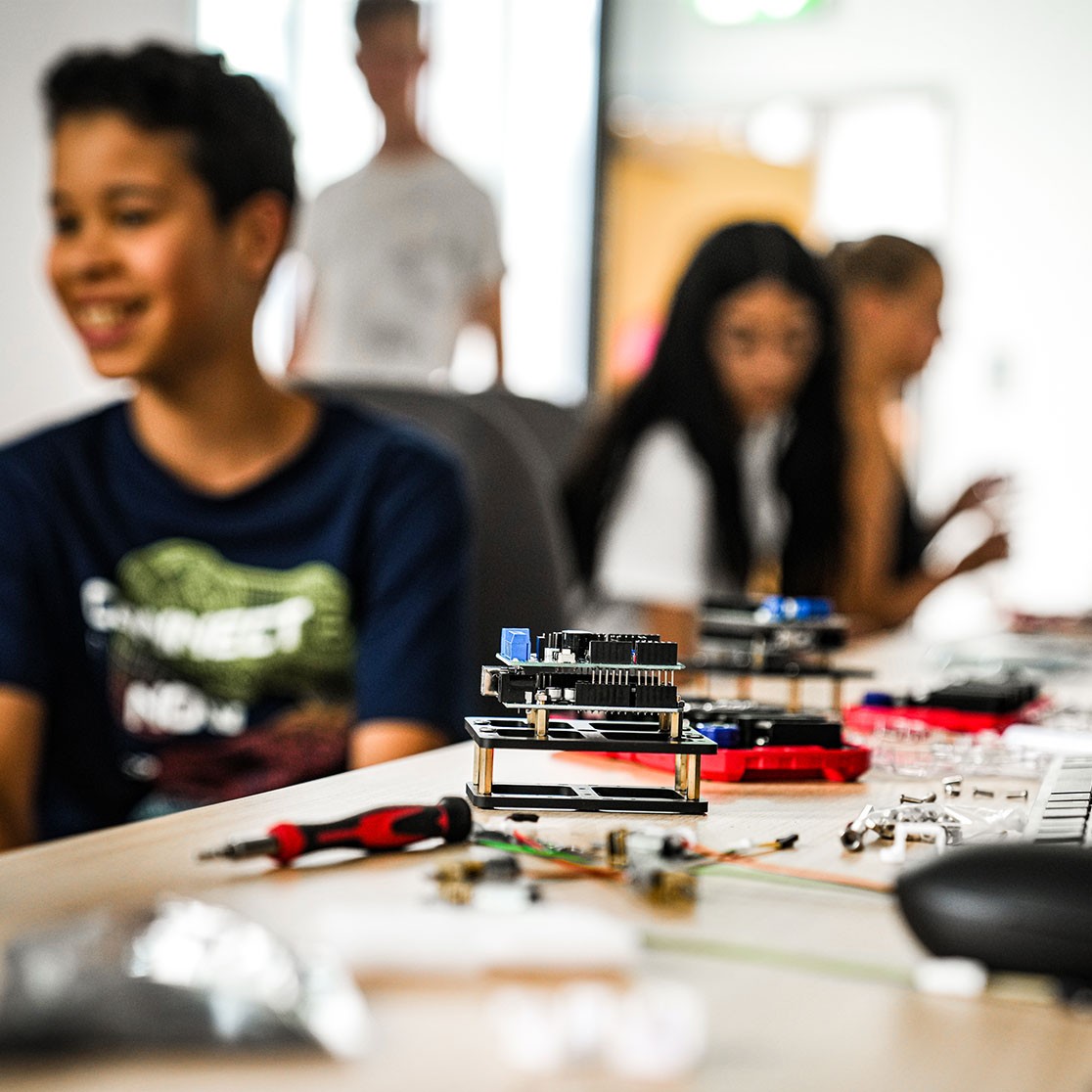Schüler arbeiten gemeinsam an einem Elektronikprojekt in einem Klassenraum.